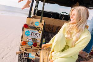 Woman on the beach next to her 30A Charity License Plate.